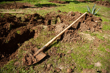 Selective focus of farming shovel on pitted soil. There is fresh soil on a used farming shovel. Gardening, spring, agriculture concept.