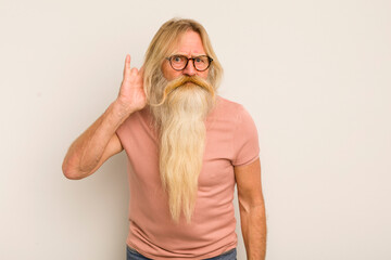 senior cool bearded man looking serious and curious, listening, trying to hear a secret...
