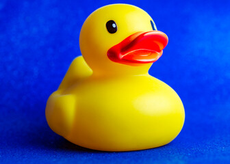 Side view of a yellow rubber duck on a blue sparkle background.