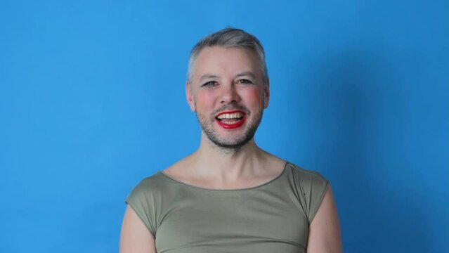 a gay man smiles broadly on an isolated blue background. lgbt. transgender