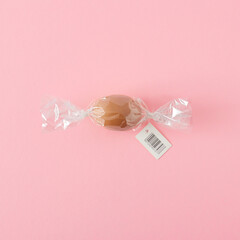 Creative Easter idea. Chicken egg wrapped like candy on pastel pink background, flat lay. Happy Easter minimal concept.