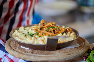 Frisch Käsespätzle mit Röstzwiebeln in einer eisernen Pfanne serviert 