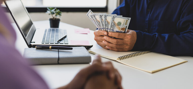The young man waited to receive salary or wages from the boss. Businessman holding cash banknotes in the office.