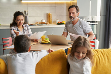 Fototapeta premium Mother addressing her children on couch during work with documents