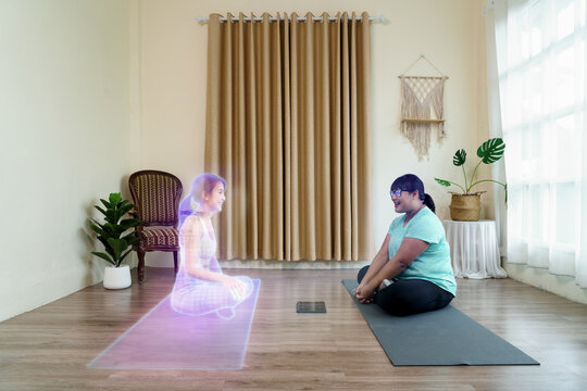 Fat woman sitting communication with yoga coach in virtual people in the metaverse platforms at home. Technology of digital world in parallel with the physical one in the future concept.