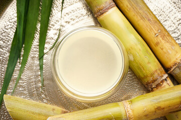 Close-up of sugarcane and fresh cane juice in a metal tray. Top view.