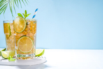 Cuba Libre, long island iced tea cocktail with strong alcohol drink, cola, lime and ice in two glass, cold longdrink mocktail on light blue tiled background