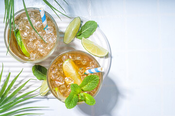 Cuba Libre, long island iced tea cocktail with strong alcohol drink, cola, lime and ice in two glass, cold longdrink mocktail on light blue tiled background