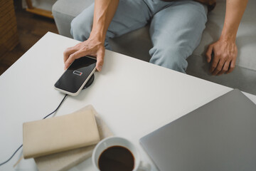 Man hands plugging a charger in a smart phone. Charging Smartphone with Wireless Charging Pad at Home