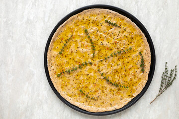 Unbaked focaccia round flat bread. Homemade pastry food with thyme herbs and salt top view.