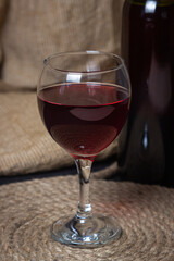 A glass of red wine on a background of burlap. Bottle of red wine. Exquisite alcoholic drink.