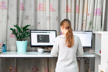 Young girl working on computer at standing desk at home office