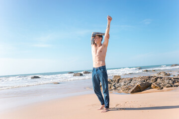 Handsome fit young caucasian bare-chested man with standing on the beach