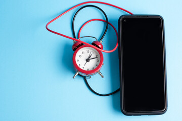 Mobile phone and clock connected  with red and black wires, conceptual  set as a external alarm clock.  