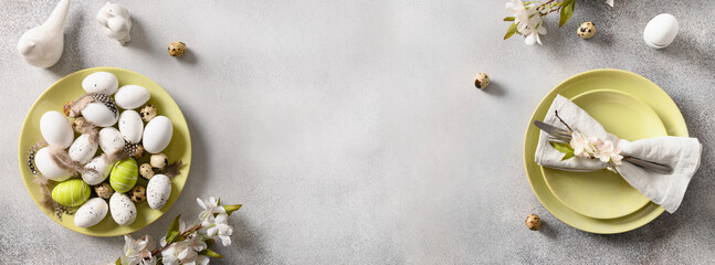 Easter eggs in green plate and spring decorations on gray background. View from above. Space for text. Concept egg dyeing. Template Easter Buffet Menu.