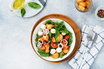 Panzanella, Italian Bread Salad. Traditional food of Italy with tomatoes, mozzarella balls, basil, onion and bread on light grey background. Traditional Italian cooking. Top view. Copy space.
