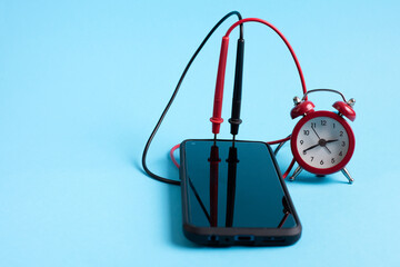 Mobile phone and clock connected  with red and black wires, conceptual  set as a external alarm clock.  