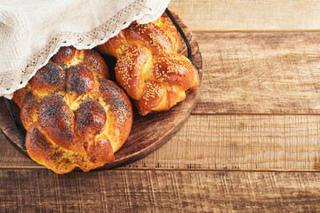 Shabbat Shalom. Bread challah with sesame seeds and poppy seeds on wooden background. Traditional jewish bread for Shabbat and Holidays. Rustic concept. Copy space. Selective focus.