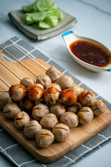 Grilled pork balls with spicy sauce on woodplate and cocumber thaicall Lukchinping