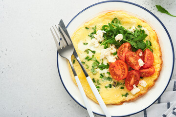 Breakfast fried eggs. Rustic omelette or frittatas with green onions, cheese mozzarella, green arugula and tomatoes on light stone background. Healthy food concept. Copy space. Top view. Mock up.