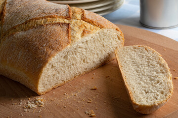 Loaf of white paysan bread, farmers bread bread, and a slice close up on a cutting board 