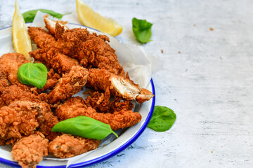 
 Crispy  deep fried   chicken strips and wedges potato. Breaded  with cornflakes chicken  breast fillets  with chilly peppers and fresh   basil on wooden rustic background