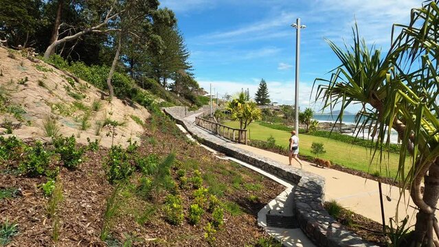 Mature woman walking her dog along the new Mooloolaba boardwalk on the Sunshine Coast, Australia.