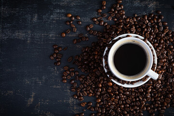 Cup of coffee with coffee beans on dark background. Mug of hot drink coffee