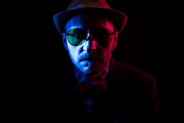 middle-aged man in a hat and aviator glasses in red and blue tones. photo in low-key