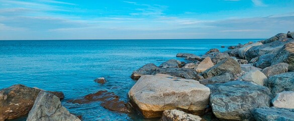 Panoramic view of big stones in the sea above blue sky. Coast of the Black Sea in Batumi. 