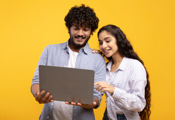 Online education, remote work and shopping. Happy indian couple looking at laptop, choosing...