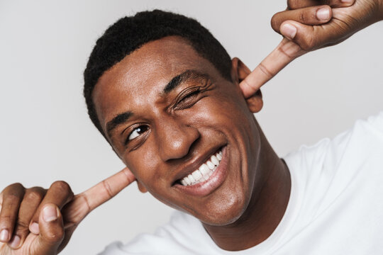 Young Black Man Smiling And Winking While Plugging His Ears