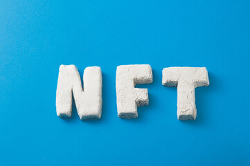 Abbreviation NFT on a blue background. Non-fungible token. - obrazy, fototapety, plakaty