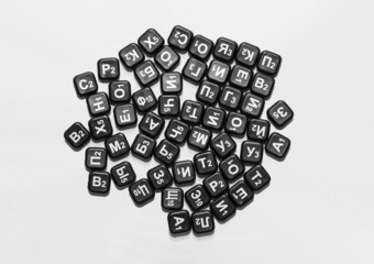 letters of the russian alphabet on black chips are scattered on a white isolated background, top view