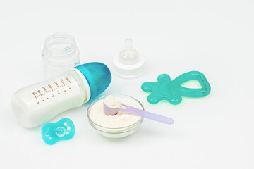 Pacifier, bottle of milk formula and rodent on the white table. Necessary purchases for newborns. Baby care kit on white background, top view, copyspace