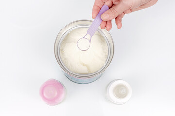 Preparation of mixture baby feeding on white background. Top view. Close up of mother's hand preparing baby formula