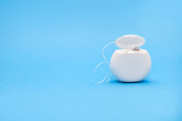 Dental floss for cleaning teeth on a blue background. The concept of oral care and caries...