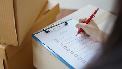 Woman checking goods package or packing before delivery or shipping to customers as order in shopping online, prepare relocate and moving to new home with checklist and order list