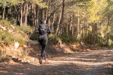 Man trail running in the mountains on a path.