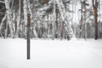 Knight sword in the snow background. The battlefield.