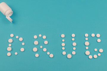 Word Drugs made of pills on blue background. Concept of treatment, tablets