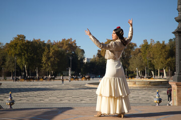 Young flamenco woman, Hispanic and brunette, in typical flamenco dance suit, with bullfighter...