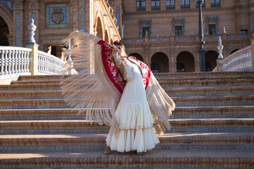 Young flamenco woman, Hispanic and brunette, in typical flamenco dance suit, dancing with red...