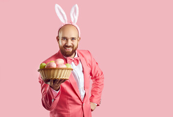 Portrait of happy funny handsome bearded young man in pink suit, bow tie and cute bunny ears...