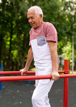 Senior man performing parallel bar exercises in park