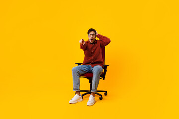 Shocked Man Pointing Finger At Camera Sitting Over Yellow Background