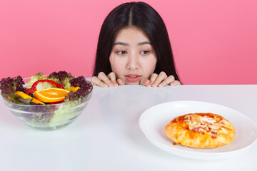 happy young asian woman choose to eat fresh orange apple fruits with copy space pink background, health care eat vegetables and useful foods lifestyles concept.