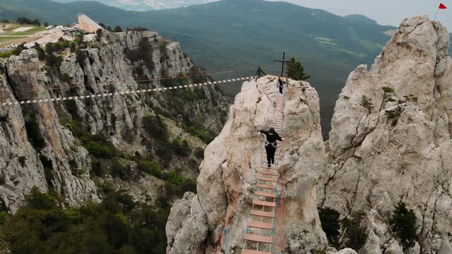 The mountains . A rope tension bridge between the rocks. A man crosses over a suspension bridge. Extreme sport.