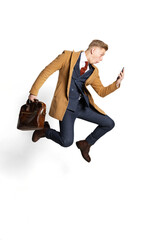 Surprised young businessman, student, diplomat jumping with smartphone isolated on white studio background. Human emotions, facial expression concept.