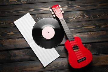 A small red toy guitar, music book and vinyls on the wooden top view background with copy space....